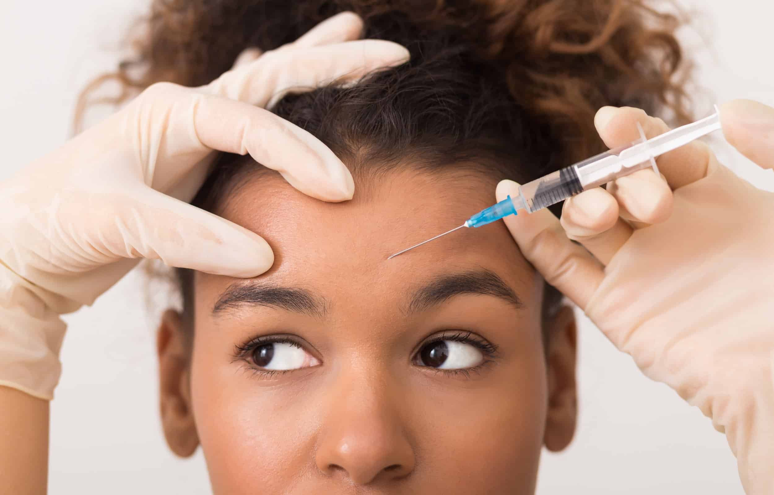 African american woman getting botox injection in forehead